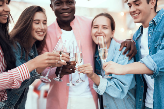 Outgoing men and cheerful females clanging glasses of champagne while speaking. Happy friends during party concept