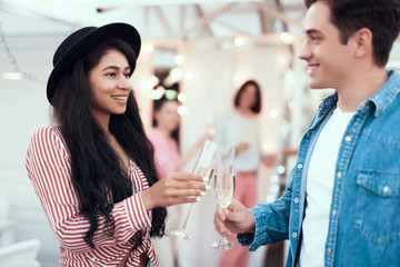 Beaming pretty lady talking with outgoing young man while tasting glass of delicious champagne