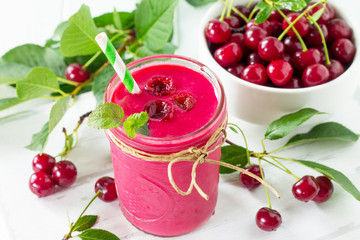 Cherry milkshake or smoothie on a white wooden background. Healthy juicy vitamin drink diet or vegan food concept.