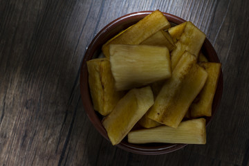 Portion of fried cassava served in earthenware bowl on rustic wooden table
