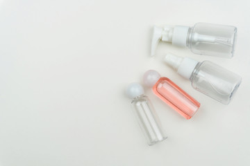 close up of a portable pink liquid plastic bottle and the three empty liquid containers on white background