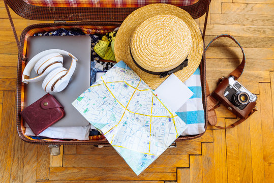 Woman Staff In Suitcase. Travel Concept. Camera Laptop Wallet Hat On Floor. Overhead View