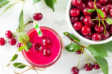Cherry milkshake or smoothie on a white wooden background. Healthy juicy vitamin drink diet or vegan food concept.