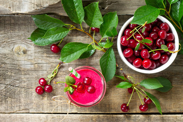 Cherry milkshake or smoothie on a dark wooden table. Healthy juicy vitamin drink diet or vegan food concept. Top view flat lay background, copy space.
