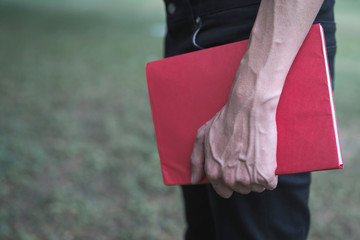 Hands holding red book.