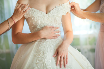 bride's girlfriend helps bride dress up her wedding dress