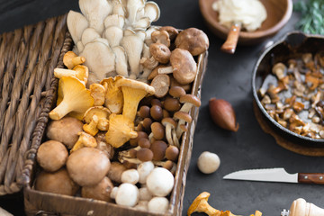 Top view of preparation and frying of edible wild mushrooms, food photo. Mix of chanterelle, portobello, shiitake in Cast-iron pan. Cooking with spices, butter, parsley, onion, leek, garlic.