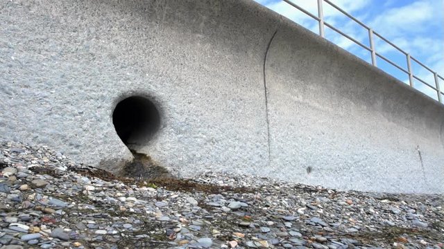 A Storm Drain Outlet set in a concrete sea wall on a shingle beach in Criccieth, Wales.