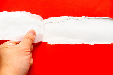 Hand tearing a red paper against white background