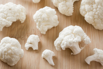 Cauliflower fresh organic, cut into small pieces on wooden background. Selective focus