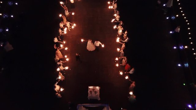 Drone flight over people waving sparklers fire, happy wedding at night.