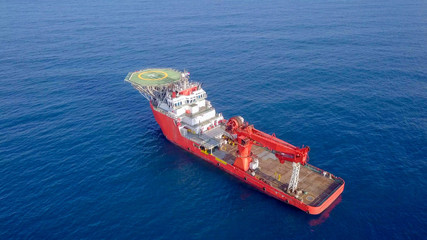Aerial image of a Medium size red Offshore supply ship with a Helipad and a large crane