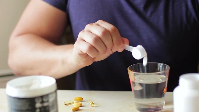 Sports supplements. The athlete prepares a portion of creatine or amino acids for consumption