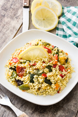 Couscous with vegetables in plate on wooden table