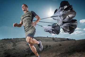 Young Man is Runs in the mountains. Functional Training of the Runner with sports Parachutes....