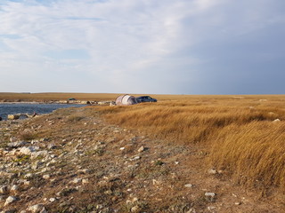 clean sky, sea and field with a tent on a sunny day