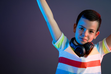 Cute boy with headphones on color liht background