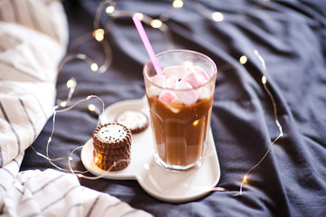 Cup of coffee with cookies in bed over lights. Good morning.