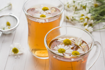 Cup of tea and chamomile flowers on wooden background
