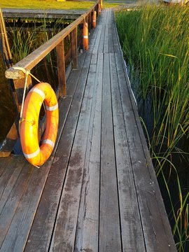 wooden pier, life ring, grass and water