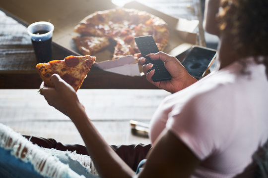 woman staying up late relaxing at home watching tv and eating pizza