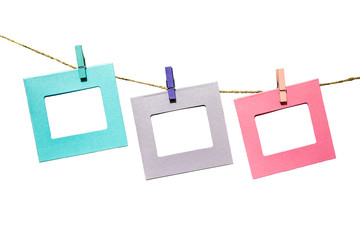 Colorful funny picture frames hanging on a rope with clothespins twine isolated on white background