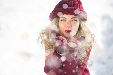 Portrait of young cheerful woman blowing snow into camera