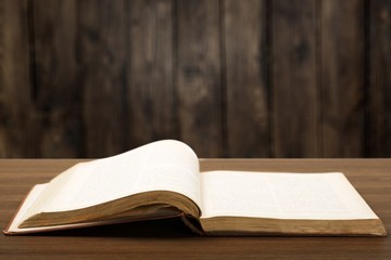 Open book on old wooden table.