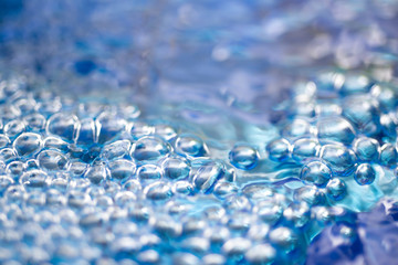 Underwater air aquamarine blue bubbles rising to water, above view, close up.