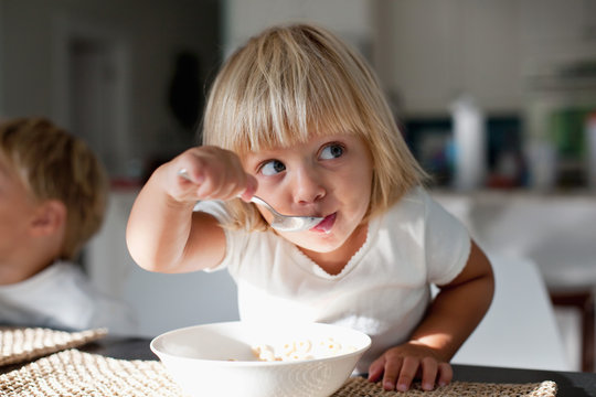 A young girl eating breakfast. 