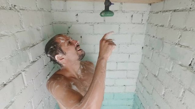 Worried caucasian foamed young man after the water in the shower was turned off. Shower breakdown or hot water shut-off.