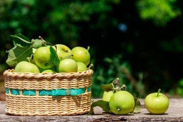 Fresh ripe apples in basket on the rustic wooden table outdoor