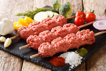 Middle Eastern Kebabs from raw minced meat on skewers with ingredients and vegetables close-up. horizontal