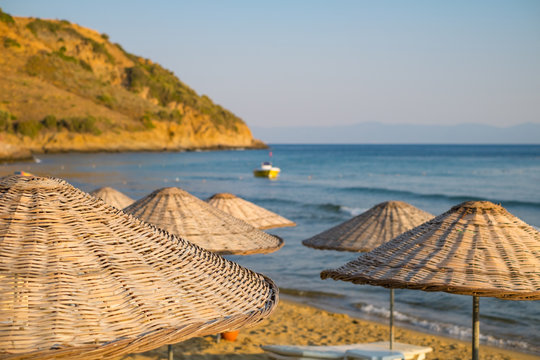 Straw umbrellas on the beach with sea and sky in the closeup background.