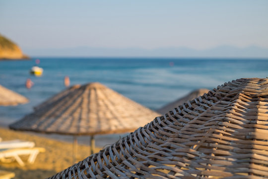 Straw umbrellas on the beach with sea and sky in the closeup background.
