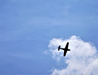 Blue sky and white clouds with silhouette of airplane flying, GA USA.