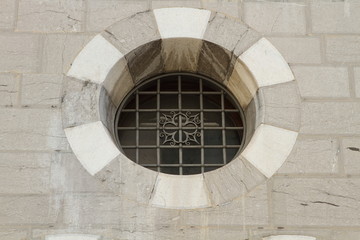 antica finestra rotonda di pietra, con sbarre ferro battutto Como, Italia