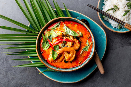THAI SHRIMPS RED CURRY. Thailand Thai tradition red curry soup with shrimps prawns and coconut milk. Panaeng Curry in blue plate on gray background