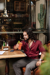 Delicious cocktail. Positive joyful man holding a glass while drinking a cocktail