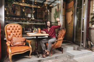Come to me. Delighted nice man looking at the waiter while sitting at the table in the cafe