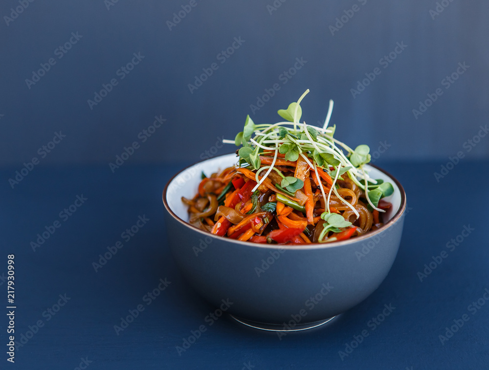 Wall mural A plate with wok vegetarian noodles with microgreen on the dark background