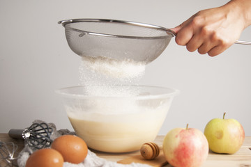 Close-up young woman's hands pourring milk, making pie, cake. Female cooking dough for pie on wooden table. Preparring dessert.