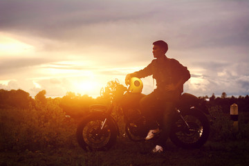 Silhouette of biker man and motorcycle with sunrise background, Rider moto trip on the street at the riverside, enjoying freedom and active lifestyle.