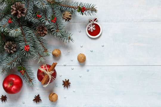 Christmas composition with red apples, walnuts, cinnamon and  other ingredients and accessories for the celebration of Christmas and New Year. Close-up, top view on light blue wooden background
