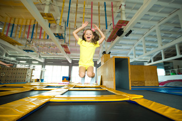 beautiful little girl jumping on a trampoline indoors