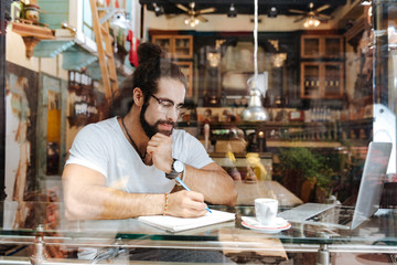 My workplace. Serious thoughtful man sitting in front of the laptop while working in the cafe