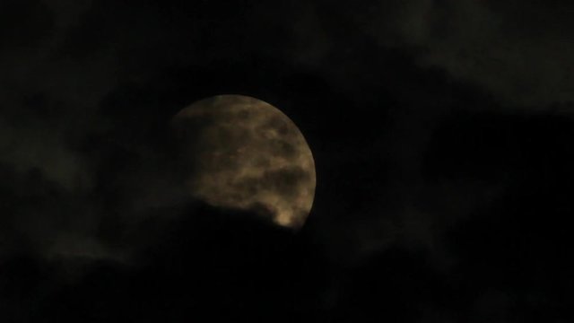 A haunting close up shot of a full moon obscured by the clouds.