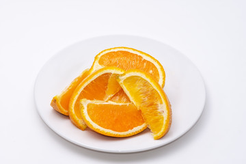Fototapeta na wymiar Pile of fresh sliced oranges on white plate with white background and room for copy text