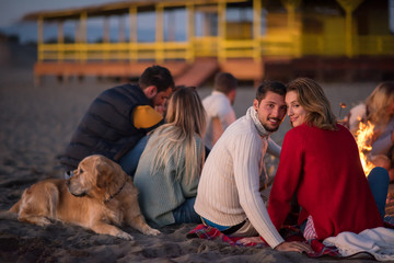 Obraz na płótnie Canvas Couple enjoying with friends at sunset on the beach