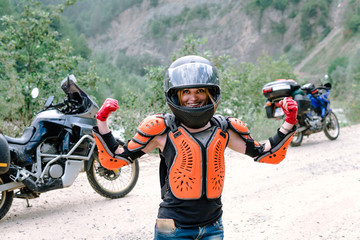 Obraz premium A girl in helmet and body armor stand alone a with two big adventure touring motorcycle with bags and camping equipment, off road travel jorney, traveling together, couple, have a power